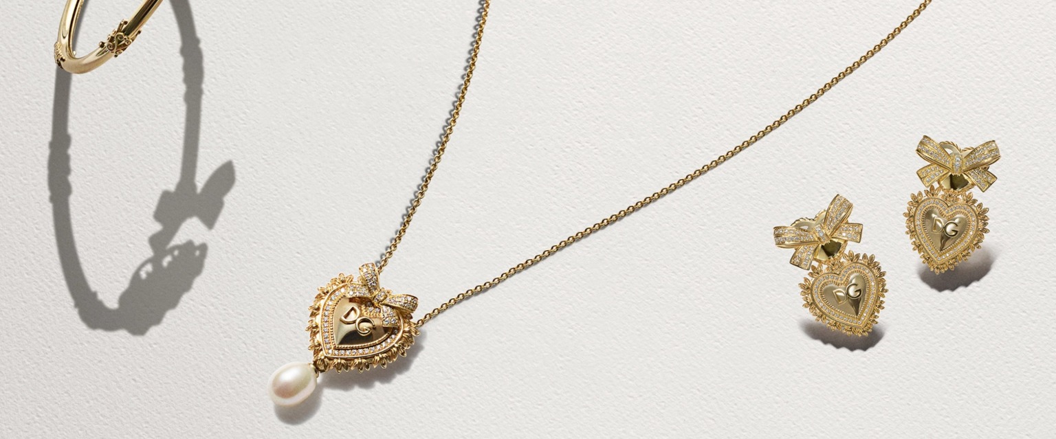 A jewelry display highlighting gold chain necklaces, cross pendants, and Devotion heart charms.